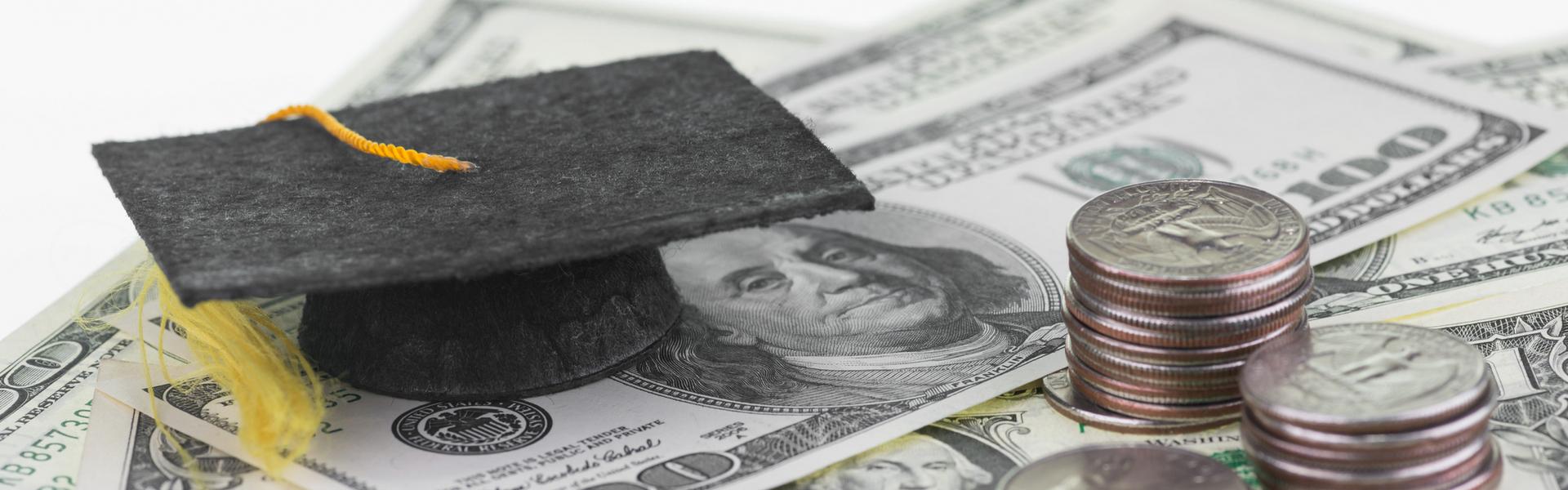A graduation cap sitting on a pile of money.