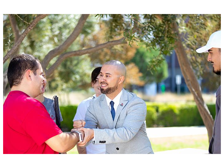 dr. Muñoz interacts with student on campus (shaking hands with a student with disability)