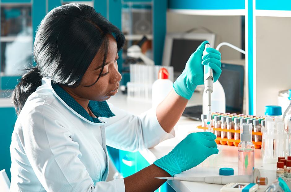 African scientist or graduate student in lab coat and protective wear performs PCR testing of patient samples in modern test laboratory. Troubleshooting of pcr kits to diagnose Covid-19 patients.