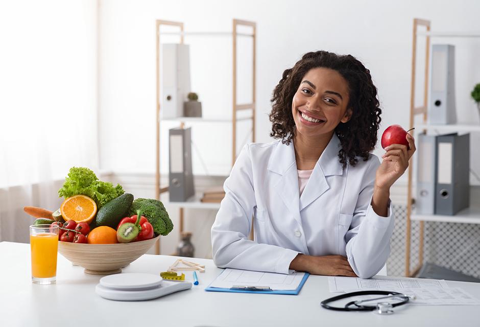 a smiling white collar woman with a fruit tray at work