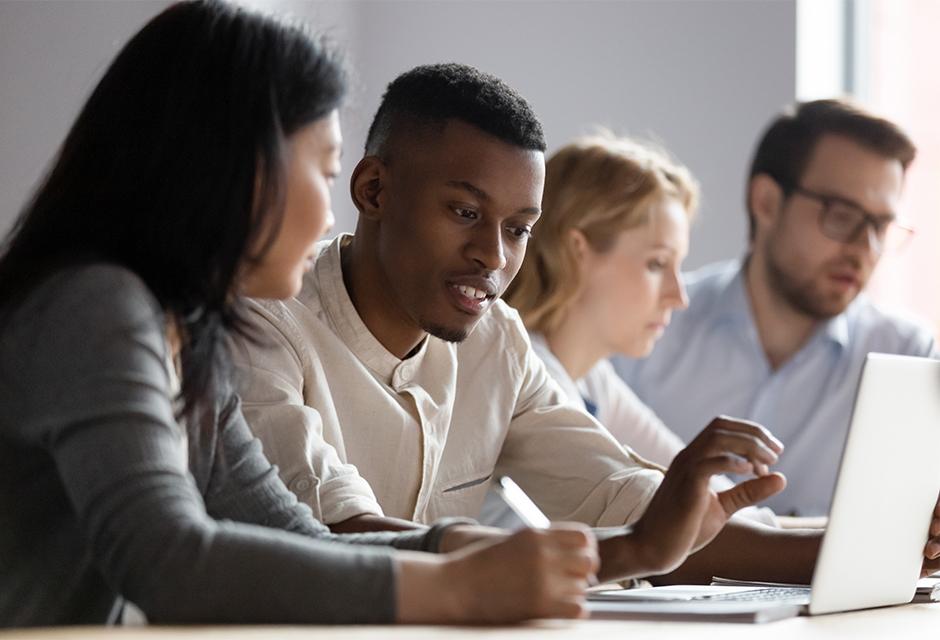 Multiethnic colleagues seated in conference room discuss new corporate app