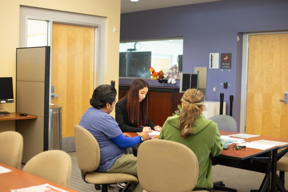 Two students using Computers in LL211 to watch orientation videos being guided by ESL student services technician