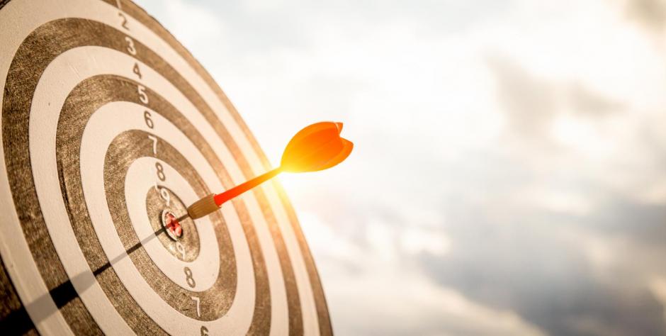 Close up shot red darts arrows in the target of dartboard center on dark blue sky background. Business target or goal success and winner concept.