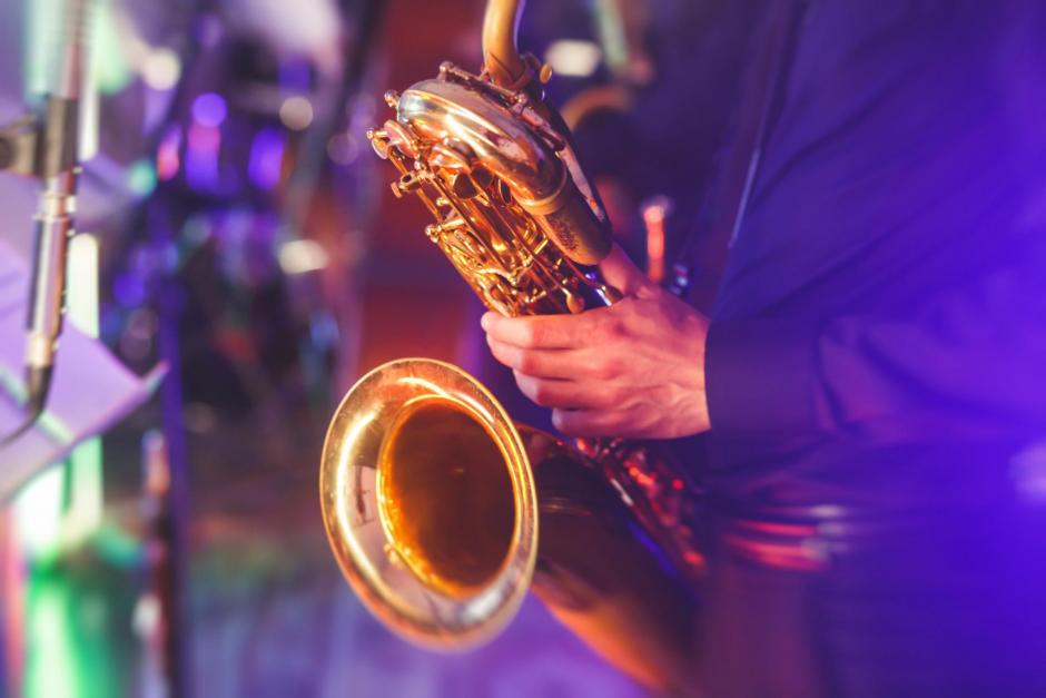 Concert view of a saxophone player with vocalist and musical jazz band in the background