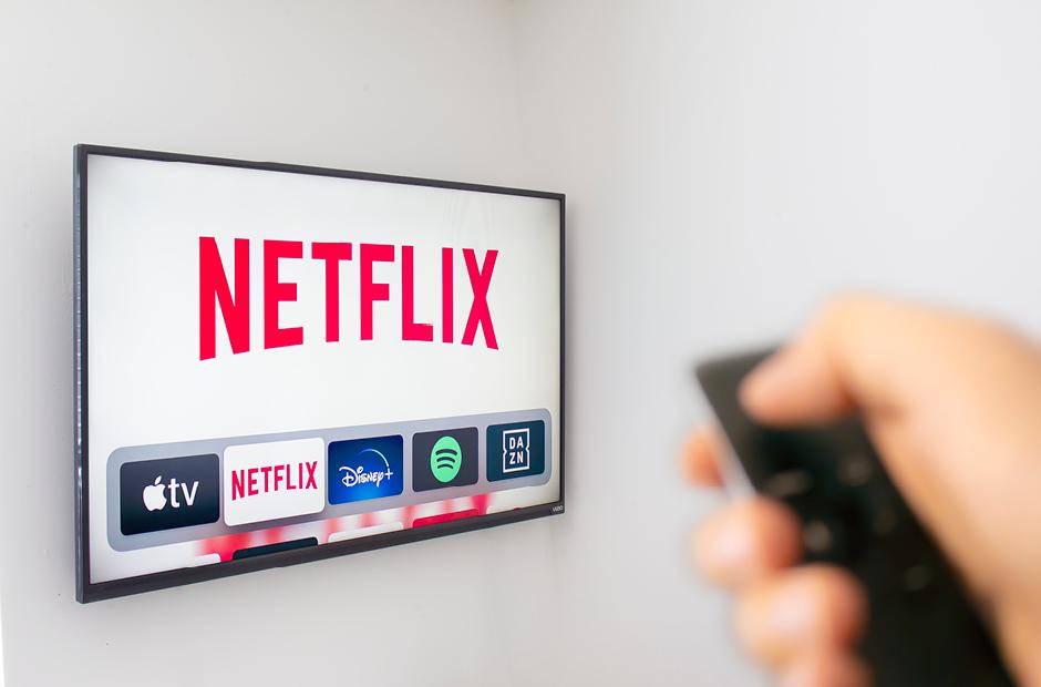 A Person holds an Apple TV remote using the new Netflix app with a hand. Netflix dominates Golden Globe Nominations. Image from iStock