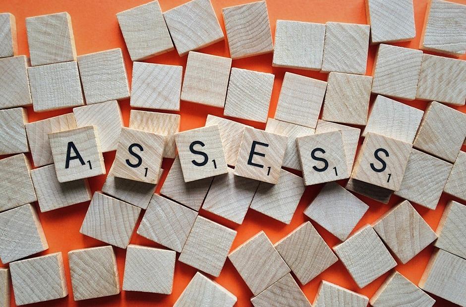 Scrabble tiles that spell the word "assess."