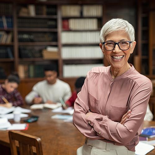Smiling college professor helping students in library 
