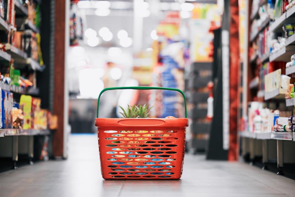 Pineapple, apple and fruit product in a red grocery basket on a floor