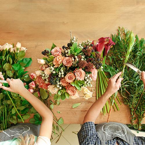 Two florists applying flower design techniques on a table