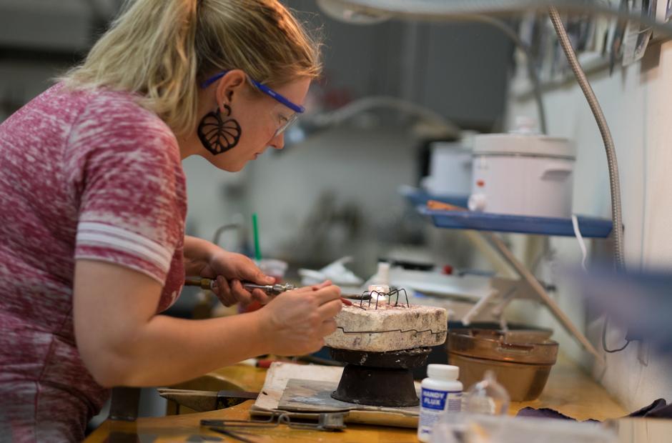 A student carefully shapes metals used in custom jewelry.