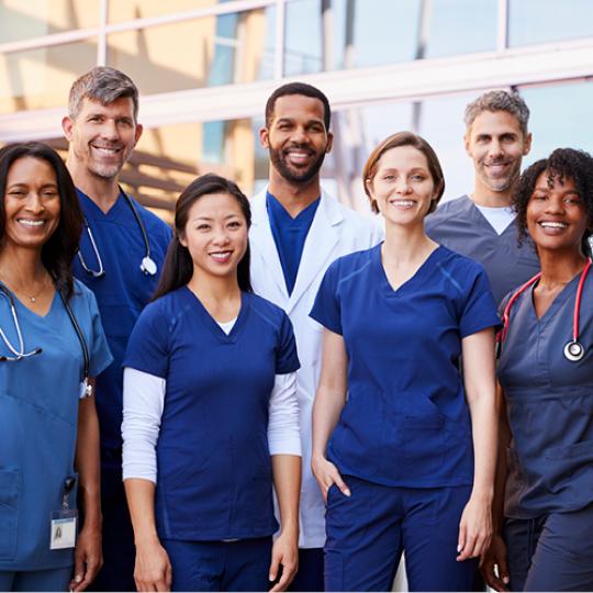 Smiling medical team standing together outside a hospital 