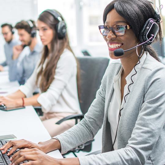 Smiling young woman with headset working in call center